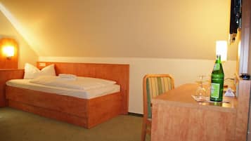 Ein Hotelzimmer mit einem Bett, einem Sessel, einem Tisch und einer Wasserflasche.