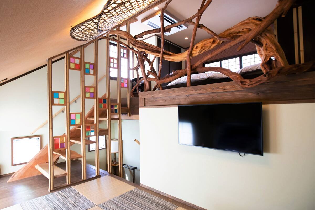 A room with a wooden staircase, a television, and a large window.