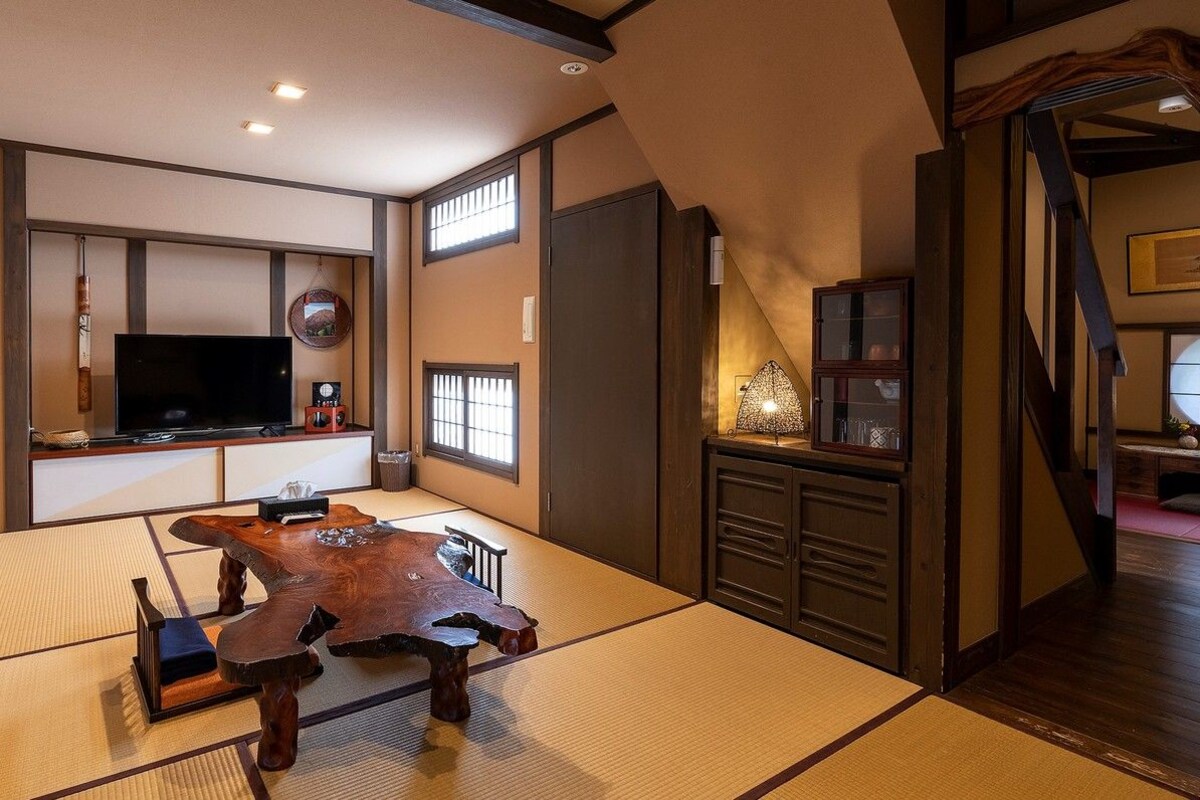 A traditional Japanese room with tatami flooring, a low wooden table, a television, and a sliding door.