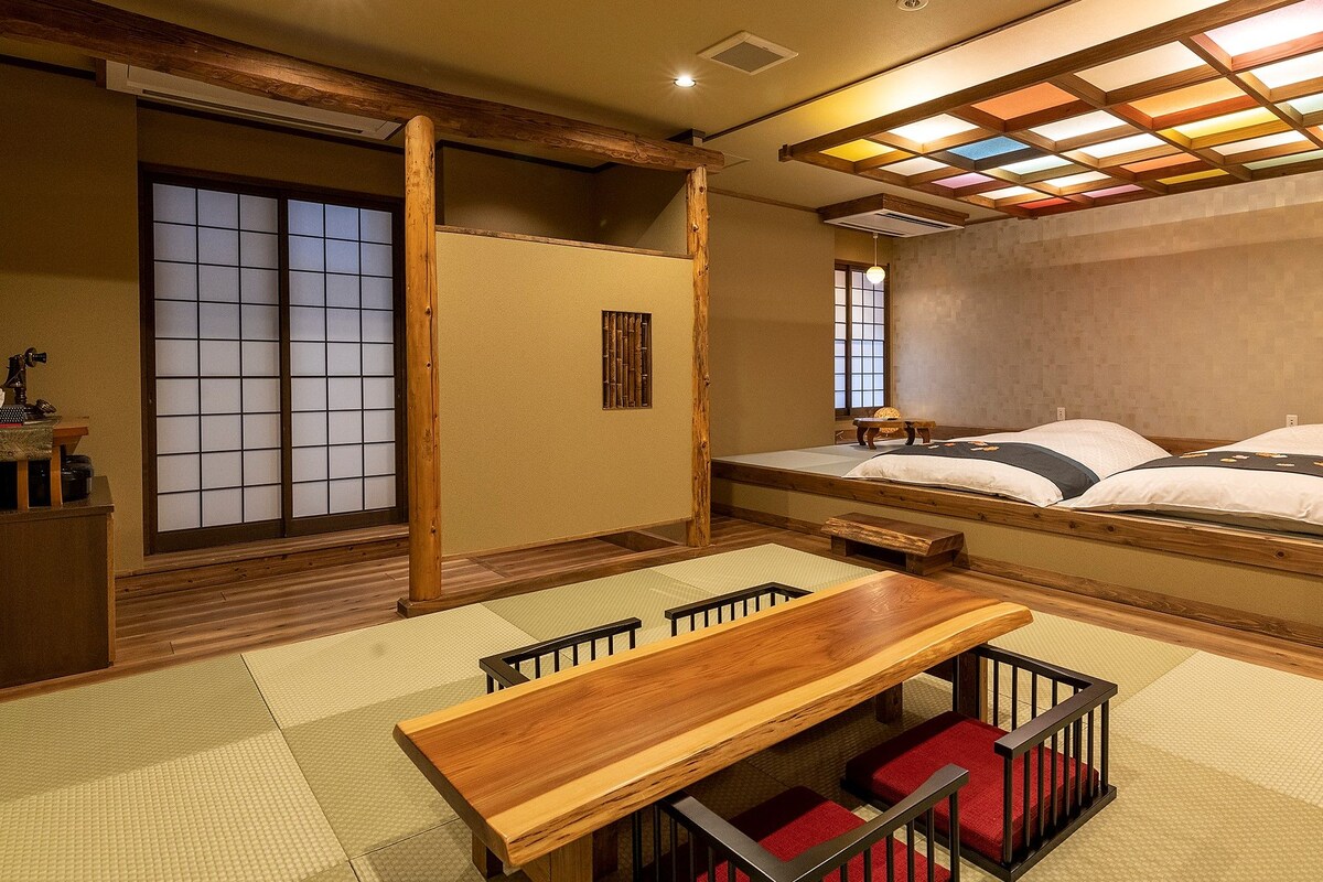 Une pièce de style japonais traditionnel, avec un sol recouvert de tatamis, un lit bas en bois, une table en bois et des portes coulissantes.