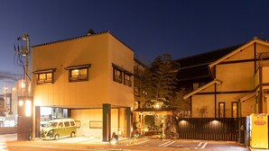 A two-story building with a flat roof, a covered entrance, and a parked van. - Dogo Onsen Atatakai Yado Taniya (Matsuyama)