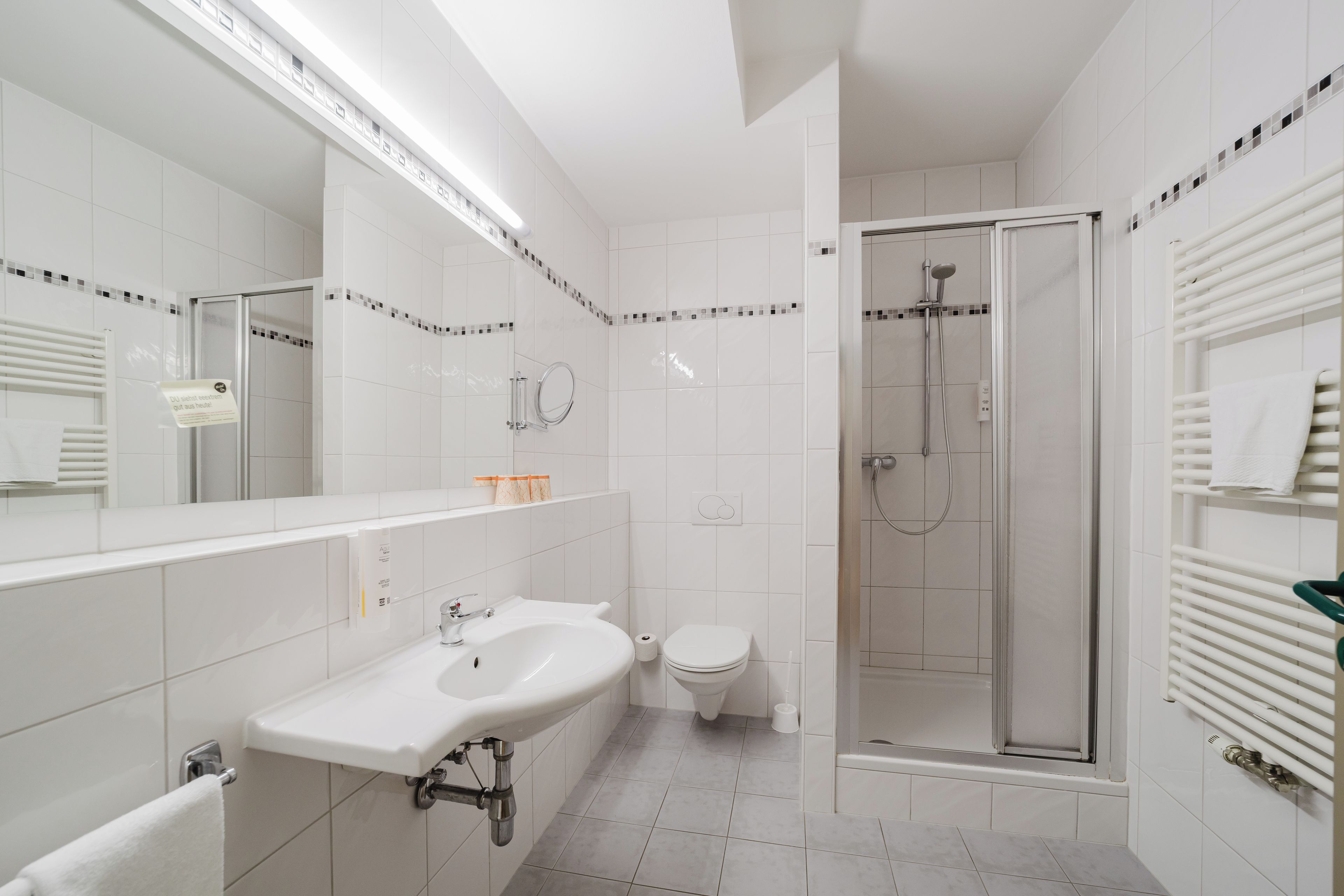 A modern bathroom with a white sink, toilet, and shower.