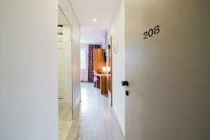 A hallway with a door labeled '208' leading to a room with a desk and chair.