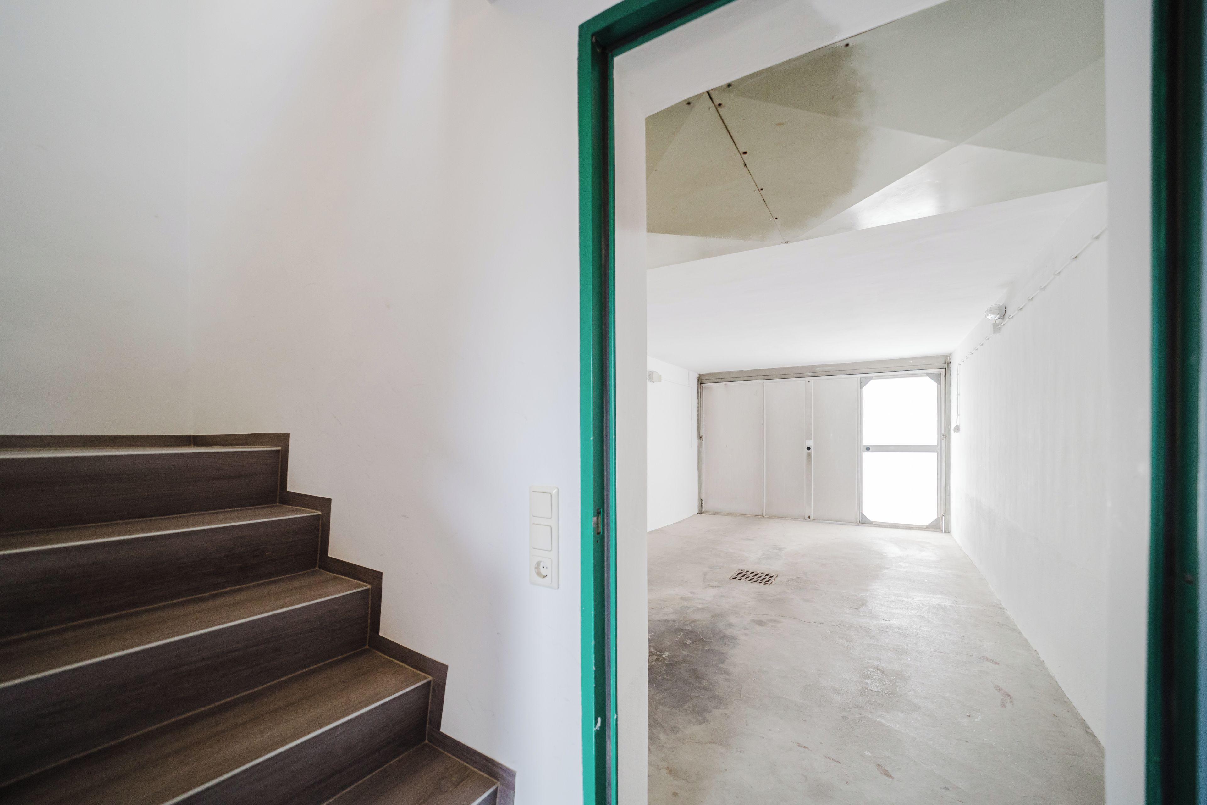 Eine Treppe führt zu einem Raum mit hoher Decke und einem großen Fenster.