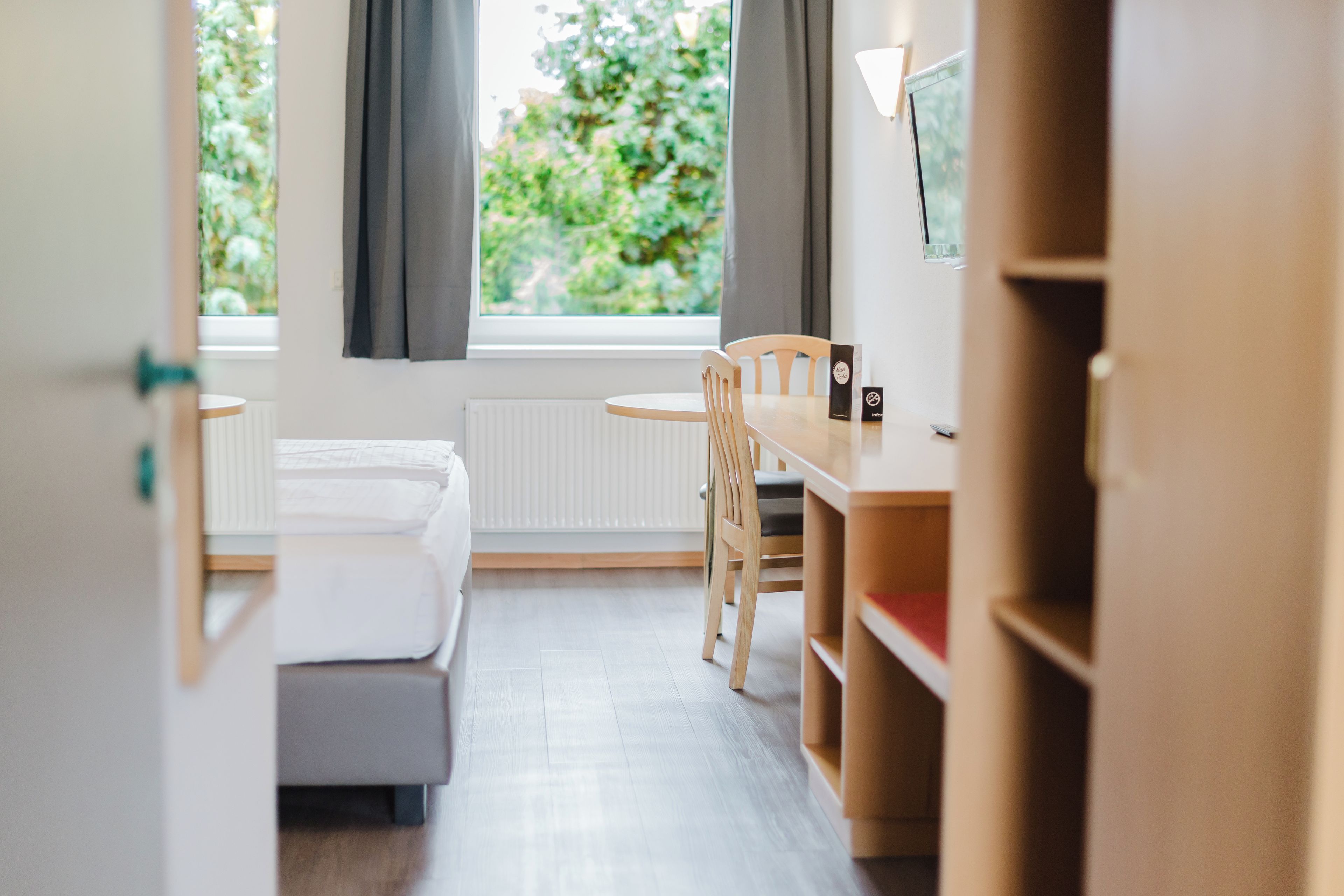 Habitación de hotel con cama, escritorio y silla. Cuenta con ventana con cortinas y vistas a zonas verdes.