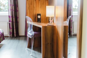 A room with a wooden table, two clear plastic chairs, a lamp, and a window with curtains. - Motel Baden (Baden)