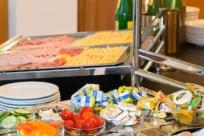 A buffet with various food items including meats, cheeses, and vegetables.