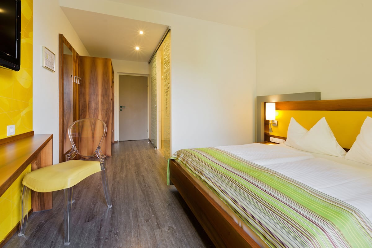Een hotelkamer met een bed, een bureau, een stoel en een televisie.