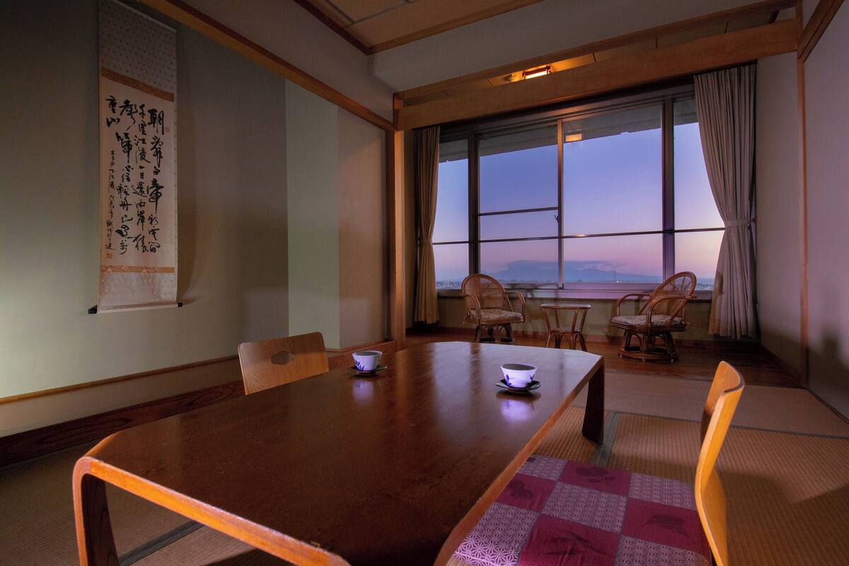 A traditional Japanese room with tatami mats, a wooden table, and chairs.