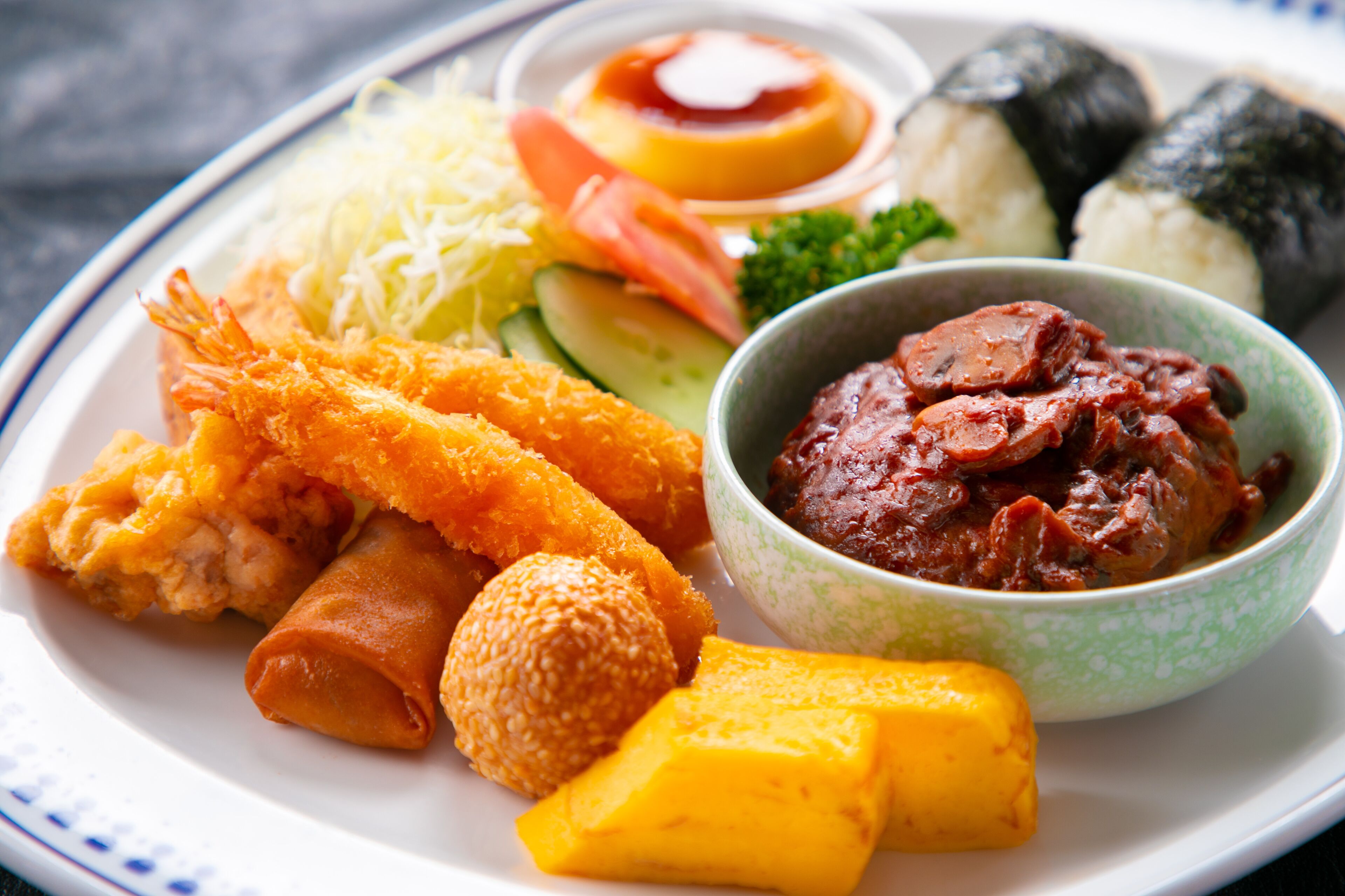 A plate of assorted Japanese dishes including tempura, sushi, and a bowl of miso soup.