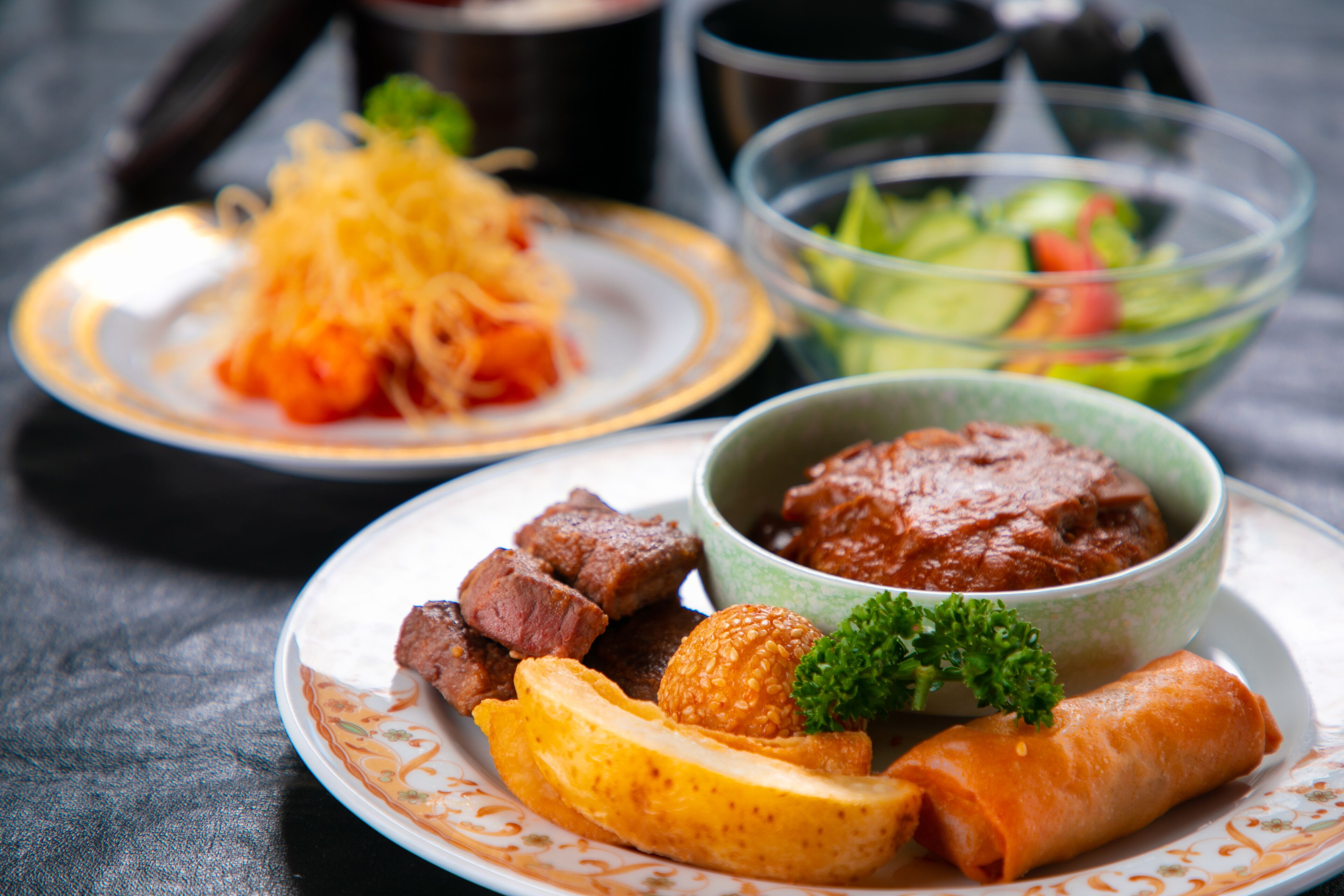 A plate with various food items including a bowl of sauce, a salad, and some meat.