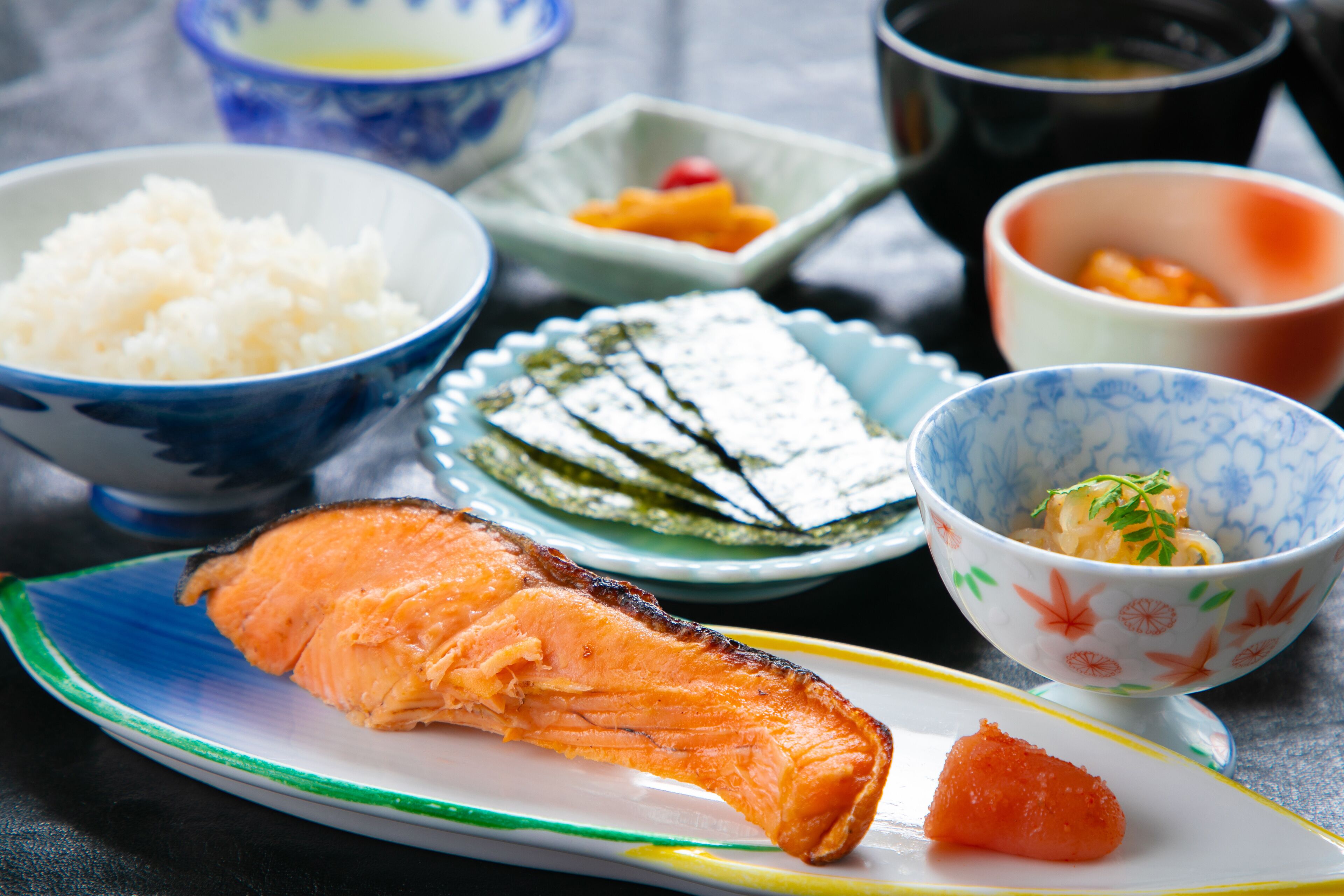 A plate with salmon, rice, and pickled vegetables.