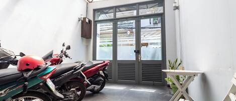 A motorcycle parked inside a covered area with a door leading to an outdoor space.
