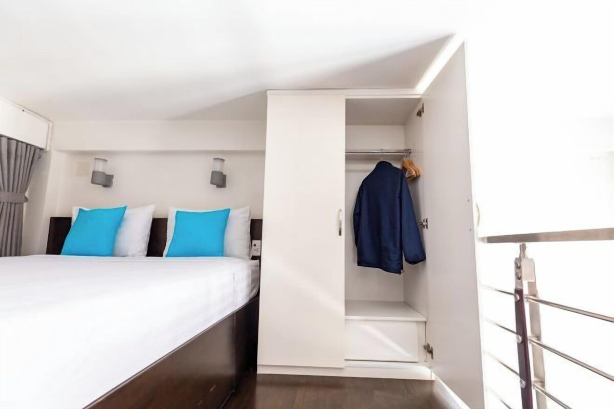 A hotel room with a bed, a wardrobe, and a small seating area.