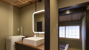 A compact hotel room with a wooden ceiling, a washbasin, a mirror, a bed with a futon, and tatami flooring. - Shirakabanoyado-Uchikyuhoji (Osaka)