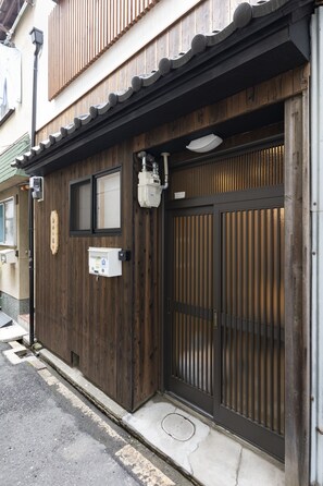 Un bâtiment traditionnel en bois, doté d’une porte marron foncé, d’une petite fenêtre et d’une enseigne.