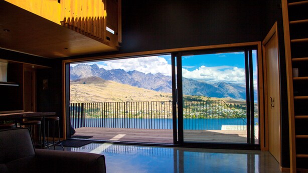 A modern interior with a large sliding glass door leading to a balcony with a mountain view. - Award Winning Architecturally Designed Pad (Queenstown)