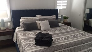A neatly made bed with a patterned bedspread, a dark headboard, and a bedside lamp. - BALBOA ISLAND WATERFRONT .... STEPS TO THE SAND (Newport Beach)
