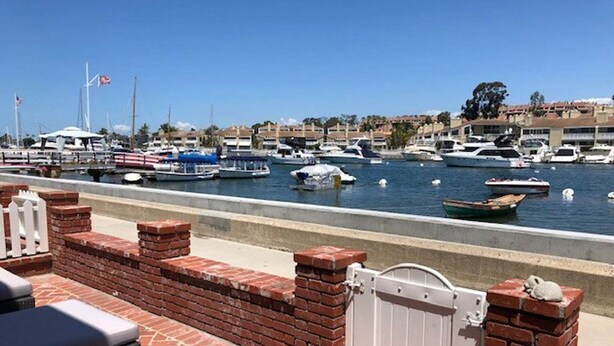 A marina with boats docked, a brick wall, and a gated entrance. - BALBOA ISLAND WATERFRONT .... STEPS TO THE SAND (Newport Beach)