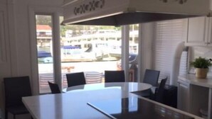 A modern kitchen with a central island, black chairs, and a view of the street outside. - BALBOA ISLAND WATERFRONT .... STEPS TO THE SAND (Newport Beach)