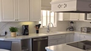 A modern kitchen with white cabinetry, a built-in dishwasher, a sink, and a stove. - BALBOA ISLAND WATERFRONT .... STEPS TO THE SAND (Newport Beach)