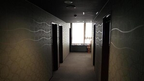 A hallway with patterned walls and doors, leading to a bright area with a window. - Hotel Palms Tenmonkan (Kagoshima)