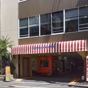 A hotel with a red and white striped awning, a red facade, and a visible entrance. - Hotel Palms Tenmonkan (Kagoshima)