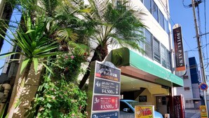 A hotel with a green awning and multiple signs advertising room rates and amenities. - Hotel Palms Tenmonkan (Kagoshima)
