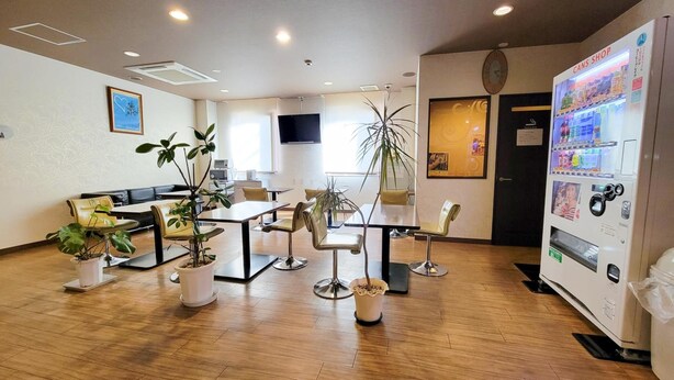 A modern indoor space with a reception area, seating arrangements, and a vending machine. - Hotel Palms Tenmonkan (Kagoshima)
