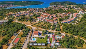 An aerial view of a coastal residential area with houses, roads, and a marina. - Apartmani Rok (Medulin)