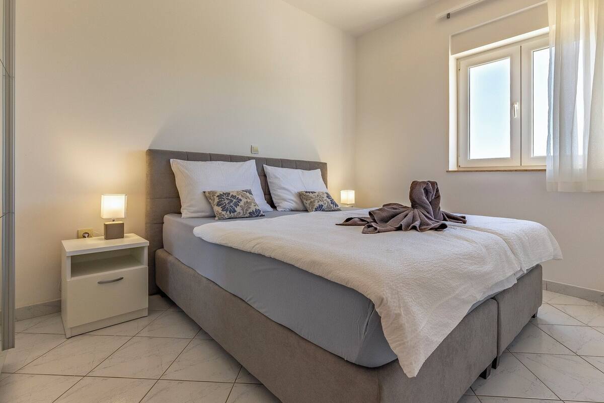 Ein Schlafzimmer mit Bett, Nachttischen, einem Fenster und Blick ins Freie.