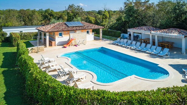 A swimming pool with lounge chairs, a slide, and a covered area with tables and chairs. - Apartmani Rok (Medulin)