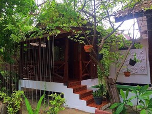 A wooden staircase leading to a covered porch with hanging plants and a potted plant on the steps. - Kirati Beach Resort (Koh Samui)
