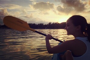 A person paddling a canoe on a body of water with a sunset in the background. - Kirati Beach Resort (Koh Samui)