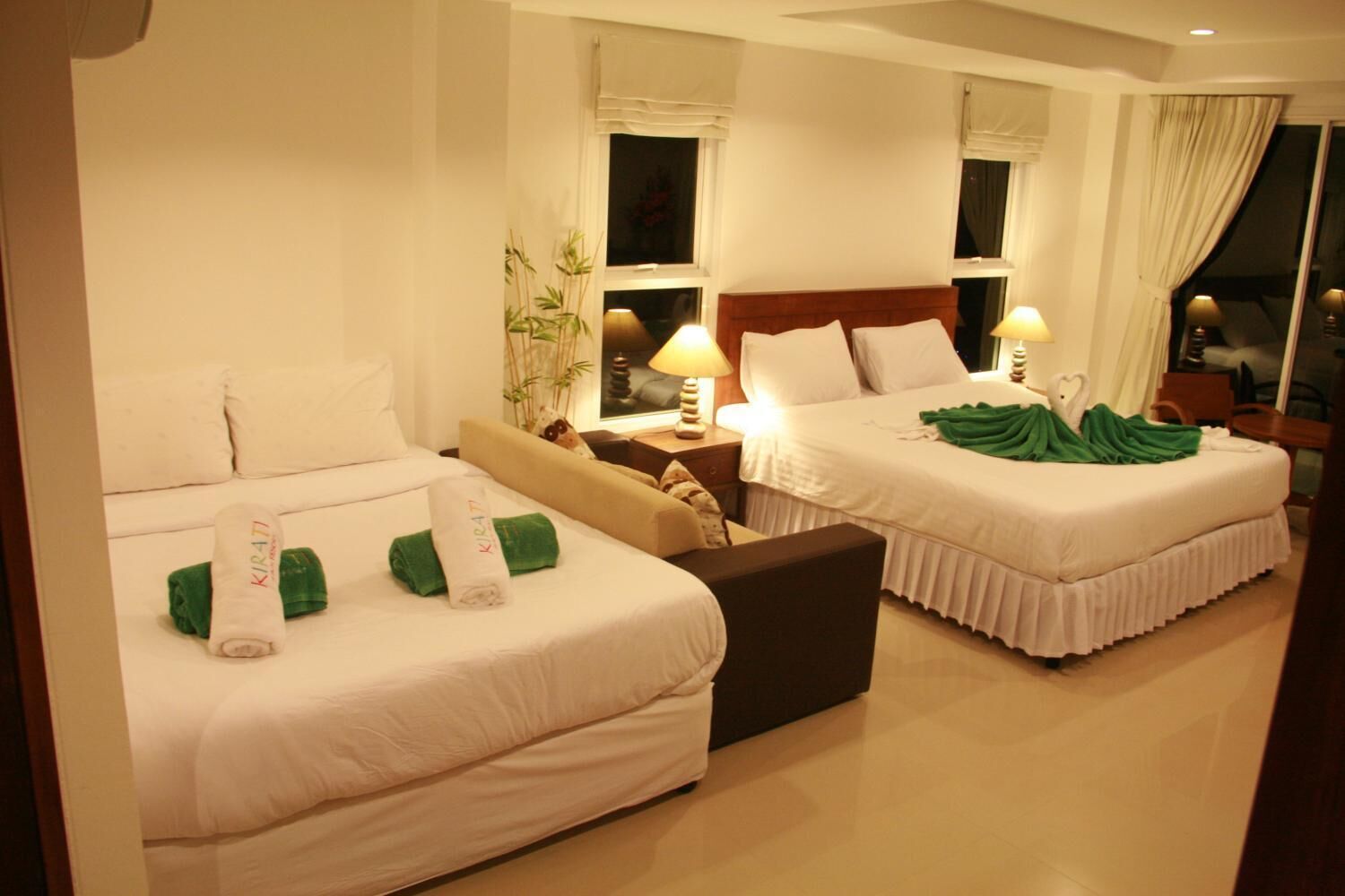 A hotel room with two beds, a sofa, and a nightstand with lamps.