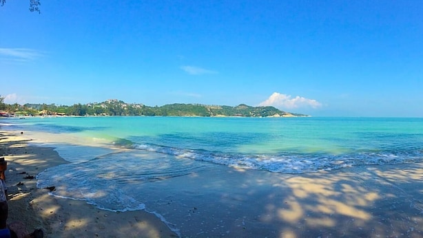 A beach with clear turquoise water, a wooden deck, and a distant view of a small island. - Kirati Beach Resort (Koh Samui)