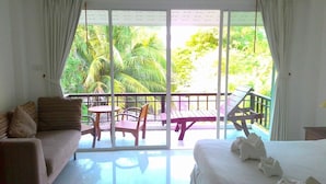 A hotel room with a balcony, a sofa, a bed, and a table with chairs. - Kirati Beach Resort (Koh Samui)