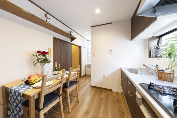 Une cuisine compacte avec des meubles en bois, un coin repas avec une table dressée pour deux personnes et une fenêtre offrant une vue agréable.