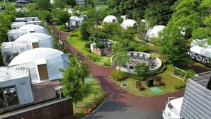 A residential area with dome-shaped houses, a central circular structure with seating, and a paved walkway. - Ufufu Village - Glamping (Izu)