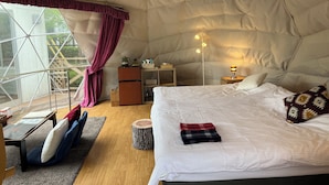 A cozy tent-style room with a bed, bedside table, lamp, and a window with curtains. - Ufufu Village - Glamping (Izu)