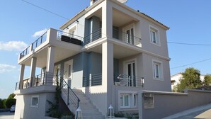 A multi-story building with balconies, a staircase, and a sign indicating 'tannos'. - Ammos Luxury Suites (Monemvasia)