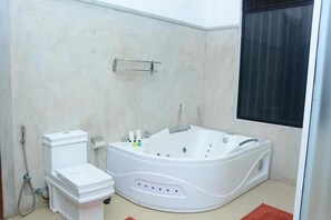 A modern bathroom with a white bathtub, toilet, and shower. - Nil diya mankada safari lodge (Udawalawa)