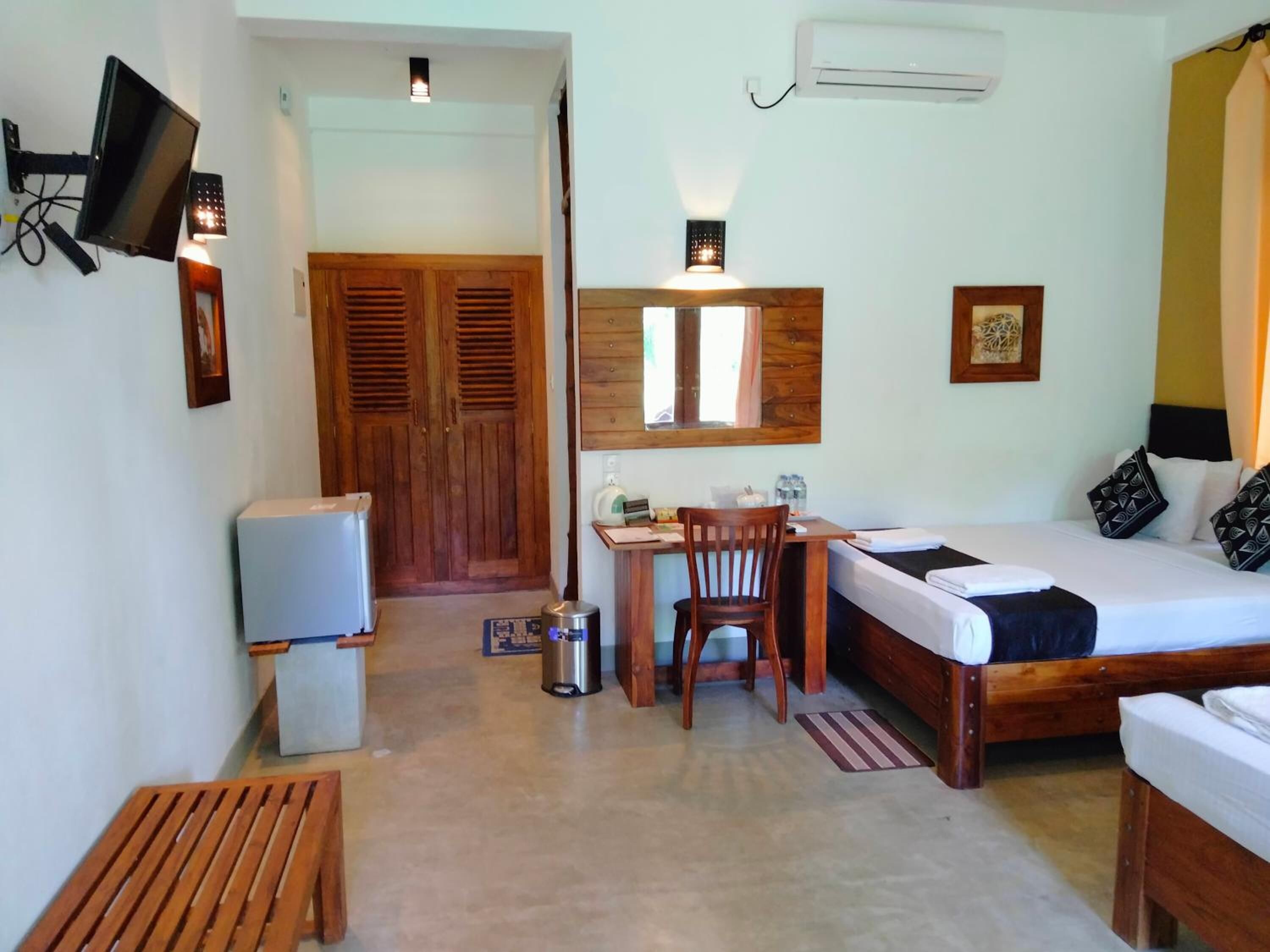 A compact hotel room with a bed, desk, chair, and a television mounted on the wall.