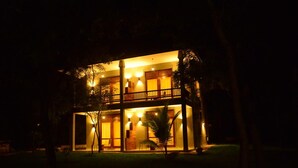 Un edificio de dos pisos con balcón e iluminación cálida.