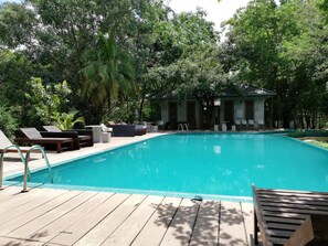 A swimming pool with lounge chairs and a small pavilion in a lush, green setting. - Nil diya mankada safari lodge (Udawalawa)