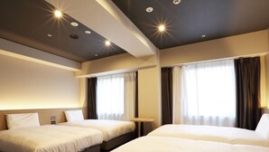 A hotel room with two beds, a small table, and a window with curtains.