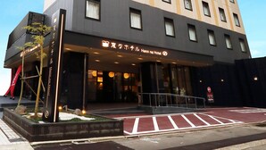 A tall hotel building with a modern design, featuring a prominent entrance with a glass facade and a sign indicating it is the Hennna Hotel.