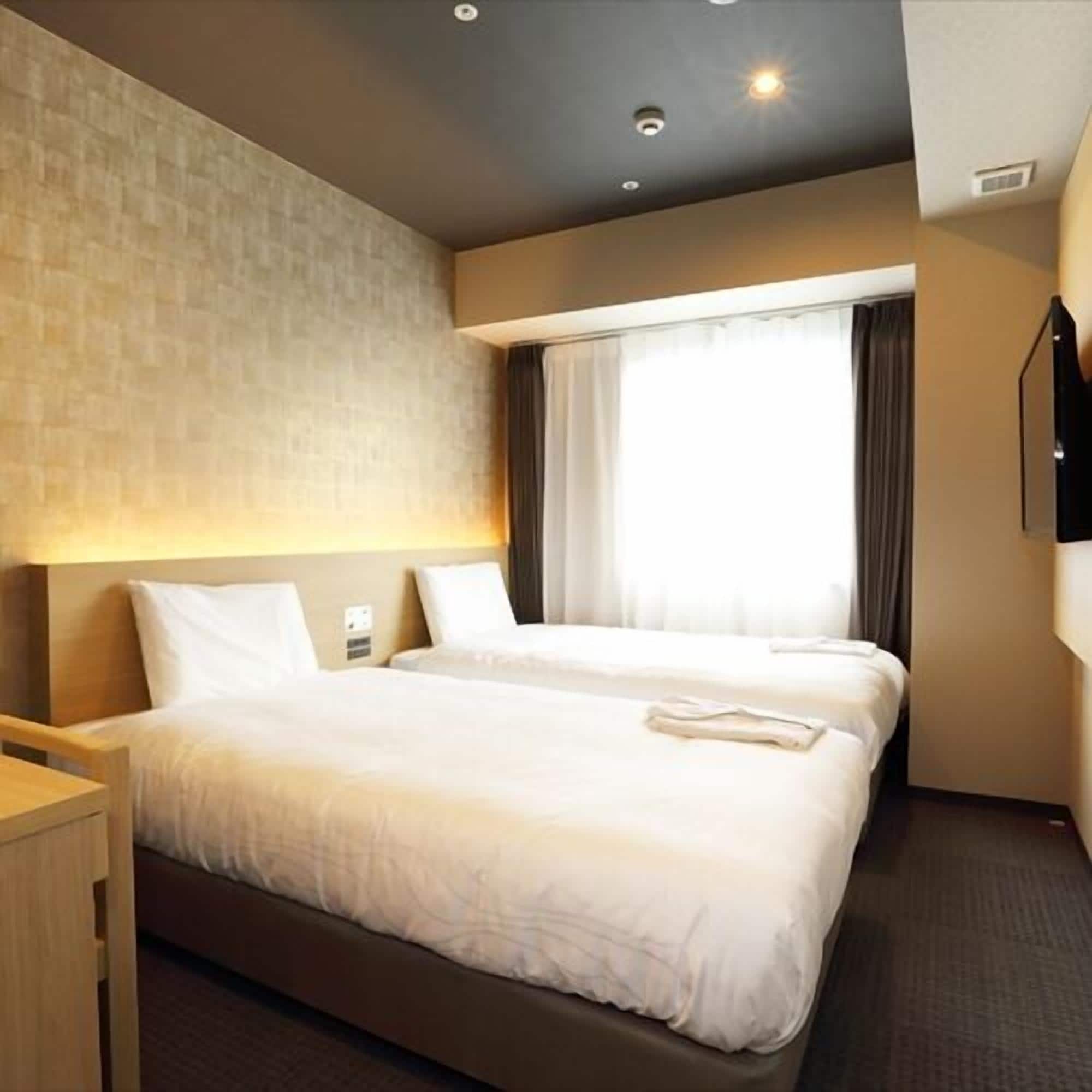 Hotelkamer met een groot bed, een nachtkastje, een wandtelevisie en een raam met gordijnen.