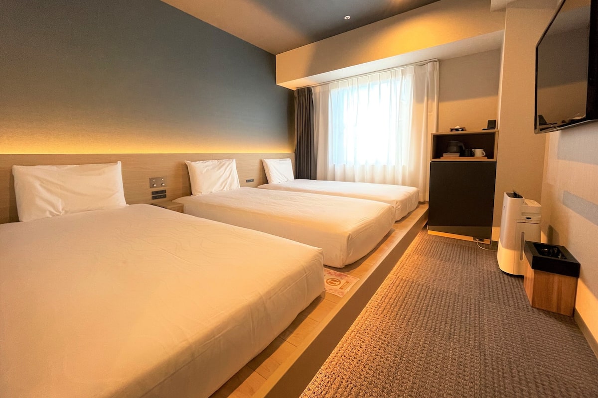 Une chambre d’hôtel avec deux lits, un bureau, une télévision et une petite kitchenette.