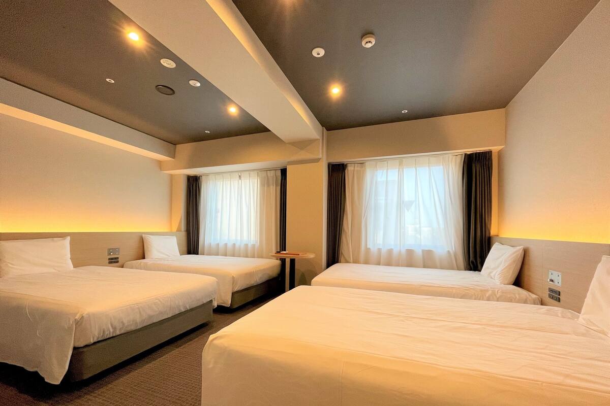 Une chambre d’hôtel avec deux lits, une petite table et un luminaire au plafond.